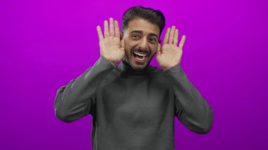 Gri balıkçı yakalı genç adam gülümseyen bir balıkçı yaka Stüdyoda açık avuçlarla el kaldırır;.