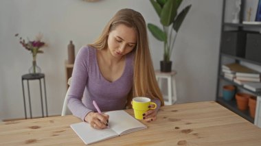 Deftere, parlak oturma odasında kahve fincanı olan bir kadın, rahat bir ortam, ahşap masa, mor gömlek, ev bitkileri, modern dekor.