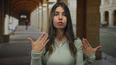 Genç İspanyol kadın, tarihi bir taş bina koridorunda elleri sıcak güneş ışığı altında kendini hayranıdır..