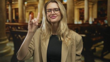 Gözlüklü sarışın kadın kilise ortamında mimar özelliklerini ve kültürel ifadesini vurgulayarak jest yapıyor..