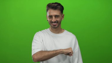 Erkek, canlı yeşil bir stüdyo duvarına karşı başparmağıyla kolunu kaldırır. Pozitiflik..