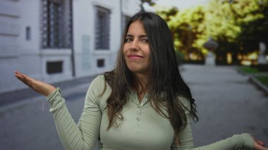 Sokakta ifade veren bir kadın, günlük giysiler giyiyor sorgulama yapıyor şehir ortamında, bulanık ağaçlarla çevrili, duygularını ve tavırlarını ifade ediyor..