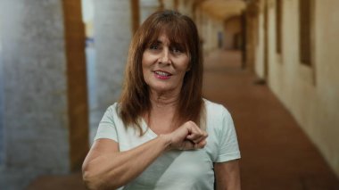 Eski bir üniversite koridorunda güvenle duran İspanyol asıllı son sınıf öğrencisi bir akademik ortamda güç ve mutluluk sergiliyor..