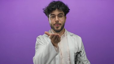 Beyaz önlüklü, sakallı ve gözlüklü genç bir adam canlı mor bir arka plana öpücük yolluyor. Arkadaşlık ve sıcaklığı büyüleyici bir ifadeyle iletiyor..