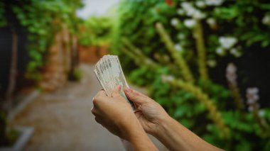 Açık bir şehir parkında kirli para tutan adam, bulanık bir arka planı olan bir şehir ortamında para ve finansmanı vurguluyor..