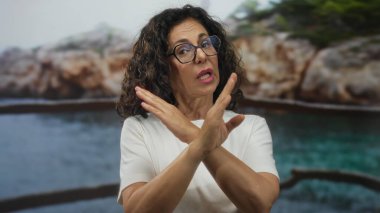 Orta yaşlı İspanyol kadın, Rocky Sahili 'nde reddedilme jesti olarak kollarını kavuşturuyor. İnatçılığı reddediyor..