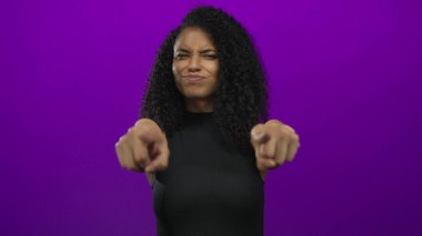 Canlı mor bir arka plana karşı neşeli bir ifadeyle işaret eden kadın