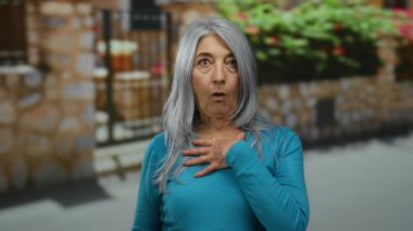 Çiçekler ve taş duvarlarla büyüleyici bir caddede dikilen bir kadın dış mekan kentsel ortamlarında son sınıf anılarını sergiliyor..