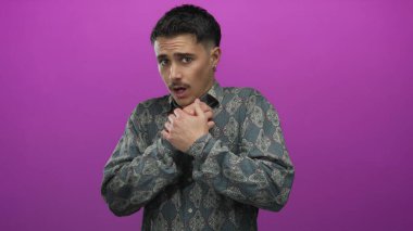 İspanyol desenli gömlekli genç adam, tecrit edilmiş pembe bir duvardan korkmuşa benziyor..