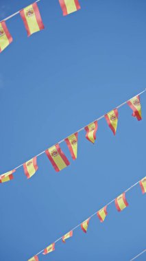 İspanya bayrakları güneşli mavi gökyüzünde dalgalanıyor İspanya 'da canlı bir açık hava kutlama atmosferi sergiliyor.