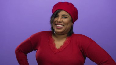 Kırmızı bereli ve kazaklı bir kadın canlı mor arka planda, neşeli ve pozitif enerjiyi somutlaştırıyor..