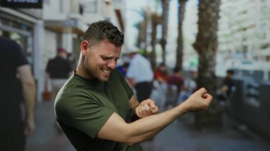 Genç bir adam hareketli bir şehir sokağında neşeli bir jest yapıyor..