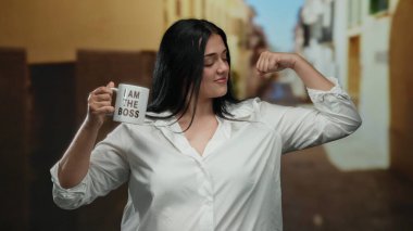 Beyaz gömlekli, kendine güvenen bir kadın elinde fincanla poz veriyor. Ben patronun şehir sokaklarında esneme hareketiyim, güç ve güç taşıyorum..