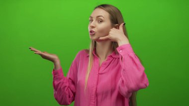 Yeşil arka planı olan, açık avuç gösteren, pembe tişört giyen bir kadın..