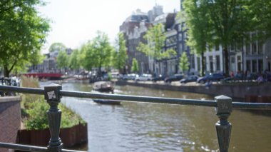 Aydınlık bir günde geleneksel evler, su ve ağaçlarla dolu büyüleyici bir kanalın bulanık görüntüsü huzurlu şehir manzarasını vurguluyor..