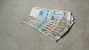 Beton bir yüzeye dağılmış 100 tabanlı Peru banknotları, para birimini ve doku detaylarını vurguluyor.