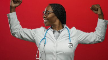 Steteskoplu, laboratuvar önlüğüyle gülümseyen kendine güvenen kadın doktor kırmızı arka plana karşı poz veriyor. Sağlık sektöründe güç ve güç gösteriyor.