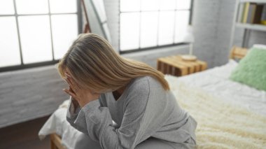 Sıcak yatak odasında, beyaz tuğlalı duvarları olan, elleri yüzü gergin bir kadın. Huzurlu bir ev ortamında bir anlık tefekkür izlenimi veriyor..