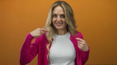 Pembe bir hırkayla turuncu bir arka planda kendini gösteren bir kadın neşeli kişiliğini ve kendine güvenen tavırlarını vurguluyor..