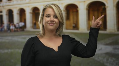 Sarışın genç bir kadın parmakla işaret ediyor. Parke Stone Caddesi 'ndeki eski kasaba binasına..