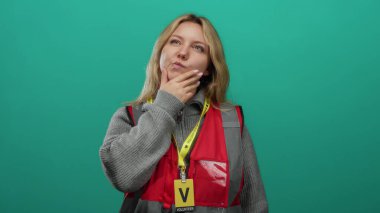 Yeşil arka planda gönüllü olan kırmızı yelekli bir kadın.