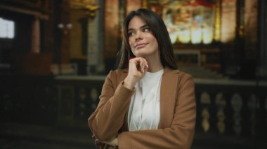 Kilise ortamında düşünen, ruhsal bir ortamda loş ışık altında düşüncelere dalan, kültürel içgözlem yapan bir kadın..