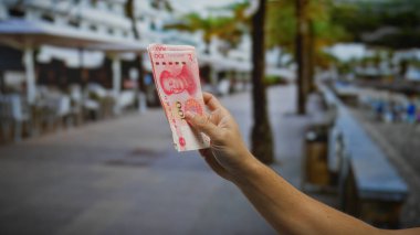 Bir şehir sokağında Çin Yuan banknotları tutan adam, canlı bir şehir ortamında para değişimi ve iş işlemlerini vurguluyor..