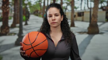Kadın, Palm-line caddesinde basketbol topunu tutuyor, sakin bir spor sahnesi sergiliyor..