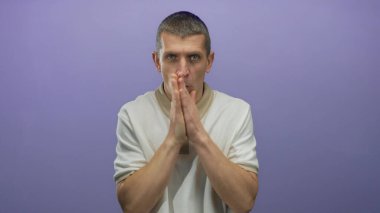 Soğuktan titreyen beyaz gömlekli bir adam izole edilmiş mor arka plan duvarına karşı..