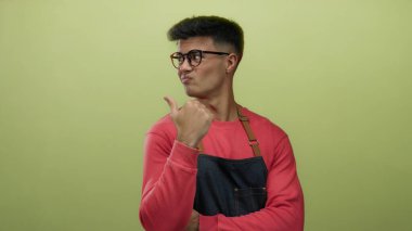 Gözlüklü genç adam sarı arka planda güvenle başparmak ucunda, rahat ve cana yakın bir tavır sergiliyor..