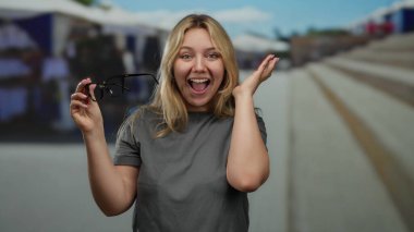 Güneşli bir günde arka planı bulanık bir şekilde elinde bardak tutan bir kadın..