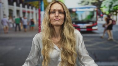 Ağzı açık bir kadın sokakta sesleniyor, genç sarışın şehir sakini gözlüklü banliyö çalışanı otobüsü selamlıyor..