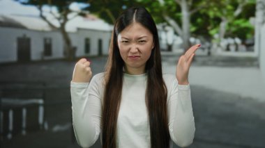 Şehir merkezinde düşünceli görünen kadın; açık havada yumruklarıyla ifade eden genç kadın..