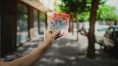 Şehrin hareketli caddesinde elinde İsviçre frangı banknotları tutan adam, şehir finans ve döviz kurunu resmediyor..