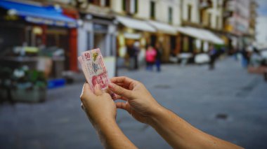 Kalabalık bir şehir caddesinde Meksika pezosu tutan adam, canlı bir şehir atmosferine para, iş ve yatırım vurguluyor..
