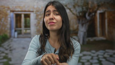 Genç İspanyol kadın avuçlarını dışarı vuruyor yaşlanmış taş binanın yanında nakit jesti için bastırıyor; çaresizlik.