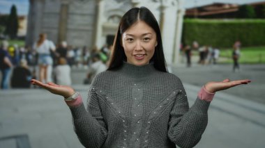 Elleri sidik kulesinin önünde gülümseyen bir kadın, İtalya, insanlarla dolu bir şehir caddesinde duruyor..