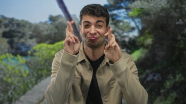 Erkek eli şans vaat ederken, İspanyol gencecik yüzlerin gülümsemesine umut yansıttığı açık bir ortamda insan parmaklarını çapraz yapmak için kaldırır..