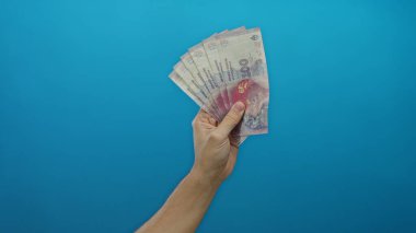 Arjantin pesolarını elinde tutan adam elinde banknotlarla mavi arka planda, beyaz erkek finans ve zenginlik kavramını gözler önüne seriyor..