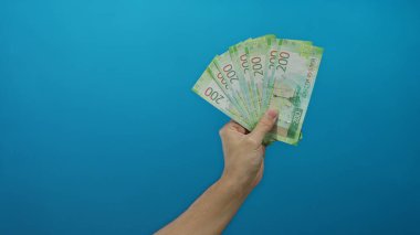 İzole edilmiş mavi bir arkaplana karşı el ele tutuşan Rus rublesi, banknotlar üzerinde bir erkeğin kavrayışını gösteriyor..