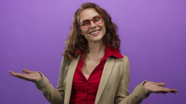 Kırmızı gözlüklü ve spor ceketli, elleri mor arka planda gülümseyen, mutluluk ve iletişimi ifade eden bir kadın..