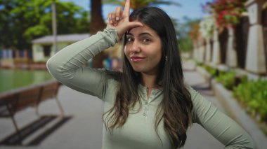 Genç İspanyol kadın güneşli yeşil bir açık hava parkında alnına ezik işareti yaptırıyor..