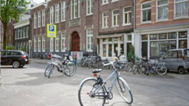 Sokakta park halindeki bisikletlerin bulanık görüntüsü, Amsterdam 'daki klasik Hollandalı binaların görüntüsü. Odaklanamayan manzara ve şehir sahnesini geliştiren bokeh etkisi..