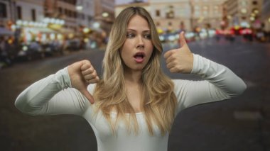 Çıplak kollu bir kadın, gece hareketli şehir caddesinde baş parmak kaldırma ve baş parmak kaldırma hareketi gösterir; kararsızlık kararsızlık.