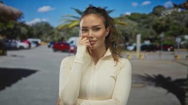 Mavi gökyüzünün altında bulanık arabalarla ve palmiye ağaçlarıyla güvenle gülen bir kadın..