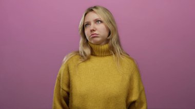 Sarı kazaklı kadın pembe arka planda dalgın görünüyor. Sarı saçlı ve sıradan giyinmiş. Gençlik tarzını ve moda ifadesini temsil ediyor..