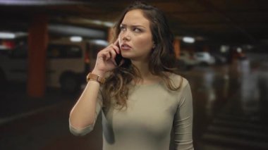 Tren istasyonunda akıllı telefondan konuşan bir kadın, tren yolunda beklerken odaklanmış bir ifadeyle beklenti ve bağlantı hissi yaratıyor..