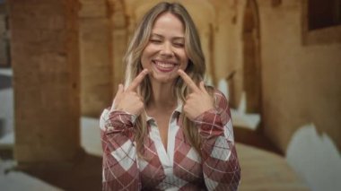 Sarı saçlı bir kadın parmaklarını manastır kemerlerinin altındaki dudaklara işaret ediyor..