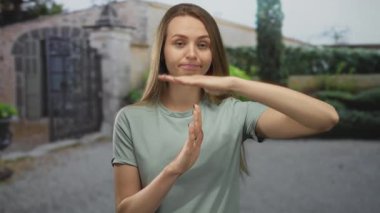 Bahçede rahat bir ifade ve açık renk giysilerle, yemyeşil ve klasik mimari ile çevrili, sakin bir öğleden sonra atmosferi olan bir kadın mola veriyor..