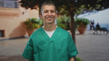 Yeşil üniformalı beyaz adam sokaklarda gülümsüyor ve bitkilerle çevrili huzurlu bir şehir ortamında öpüşüyor..